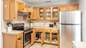 A kitchen with wooden cabinets, a stainless steel refrigerator, and a built-in oven. - Clean+Cozy+Close to Airport/Jackson/Dogwood Ctr! (Brandon)