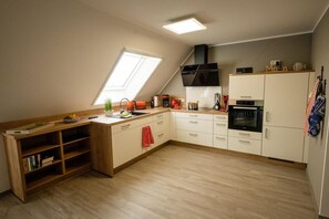 A compact kitchen with a skylight, built-in bookshelves, a stove, and a microwave.