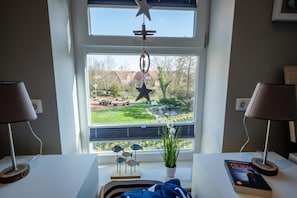 A room with a large window, a star hanging from the ceiling, a potted plant, and a book on the windowsill.
