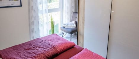 A bedroom with two beds, a desk, and a wardrobe.