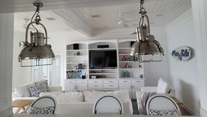 Un coin repas avec une table blanche, des chaises et un meuble blanc avec des étagères.