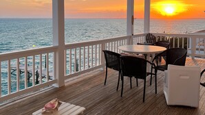 A covered outdoor area with a wooden deck, white railing, and a table with chairs. - Large waterfront Home on Lubbers with Private Boat Dock (Hope Town)
