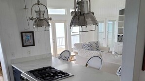 Une cuisine dotée d’un grand îlot central, d’appareils électroménagers en acier inoxydable et de luminaires suspendus.
