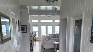 Un hall d’entrée spacieux, doté d’un parquet en bois, agrémenté d’un tapis central, et comprenant un coin repas avec une table et des chaises.