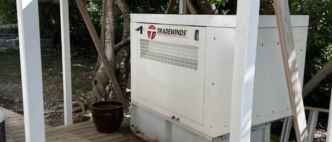 Een witte buitenconstructie met een geïnstalleerde airconditioning unit, genaamd “Tradewinds”, op een houten terras.