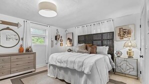 Een slaapkamer met een bed, een dressoir, nachtkastje en decoratieve objecten.