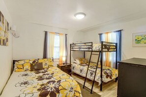 Ein Zimmer mit zwei Betten, einem Etagenbett, einem Schreibtisch und einer Deckenleuchte.