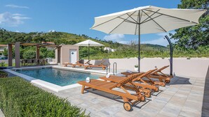 A poolside area with lounge chairs, a pool, and a pergola. - Stunning home in Tugare (Tugare)