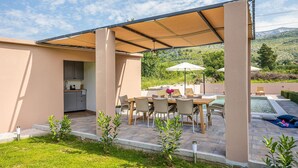 A covered outdoor dining area with a pool, a kitchen, and a view of the surrounding landscape. - Stunning home in Tugare (Tugare)
