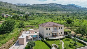 A two-story house with a balcony, a swimming pool, and a well-maintained garden. - Stunning home in Tugare (Tugare)
