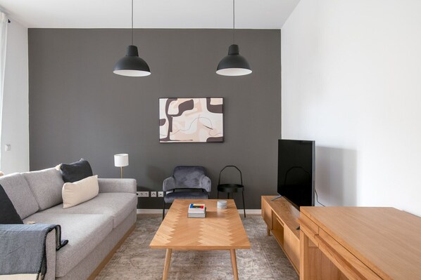Relax in this stylish living room with a sofa, armchair, and large TV.