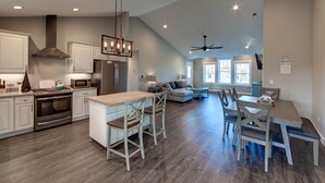 A spacious kitchen with modern appliances, a dining area with wooden chairs, and a ceiling fan. - New construction home short walk to the beach! (Avon)