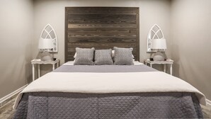 A neatly made bed with a quilted bedspread, two pillows, and a wooden headboard. There are two bedside lamps on white nightstands. - Melanie Park Raider Cottagecore Design 4/3 (Lubbock)