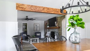 A dining area with a wooden table, chairs, and a vase with green leaves. - Melanie Park Raider Cottagecore Design 4/3 (Lubbock)