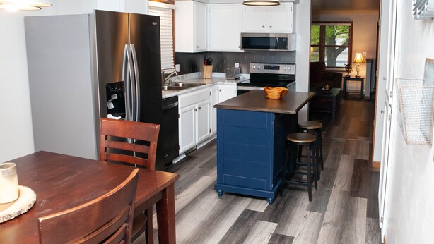 A modern kitchen with white cabinets, stainless steel appliances, and a blue island. - 2 Bedroom, 1 Bathroom Convenient Green Bay Getaway (Bellevue)