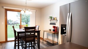 A modern kitchen with a dining table, chairs, a refrigerator, and a coffee machine. - 2 Bedroom, 1 Bathroom Convenient Green Bay Getaway (Bellevue)