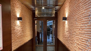Un pasillo con paredes de ladrillo, paneles de madera y suelo de baldosas.