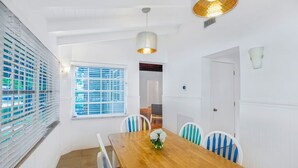 A dining area with a wooden table, white chairs, and a hanging light fixture.