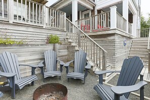 En träveranda med Adirondack-stolar och en eldstad.