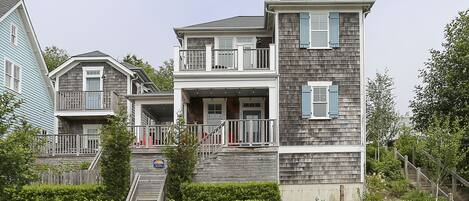 A two-story house with a balcony, a front porch, and a staircase leading to the entrance.