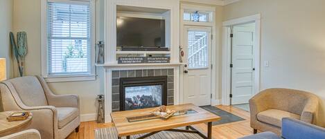 Una sala de estar con chimenea, dos sofás, una mesa de centro y un televisor.