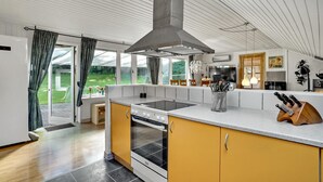 A modern kitchen with a large island, a built-in oven, and a stainless steel range hood. - Lovely home in Roslev with WiFi (Roslev)