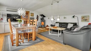 A modern living room with a wooden dining table, grey sofa, and a fireplace. - Lovely home in Roslev with WiFi (Roslev)