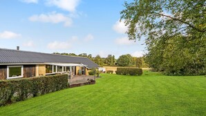 A house with a covered patio, a lawn, and a large tree. - Lovely home in Roslev with WiFi (Roslev)