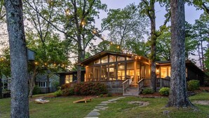 A house with a large glass front, a wooden deck, and a stone pathway leading to the entrance. - Peaceful Lakeside | Stunning Views | Private Dock (Hot Springs)