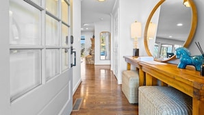 A hallway with a wooden floor, a mirror, a lamp, and wicker furniture. - Peaceful Lakeside | Stunning Views | Private Dock (Hot Springs)