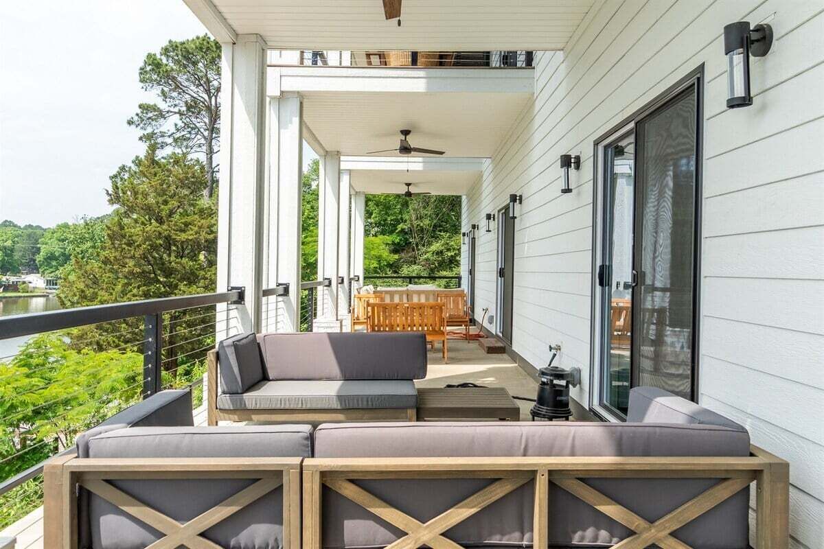 A covered outdoor seating area with a sofa and chairs, a table, and a ceiling fan.