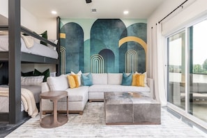 A modern interior with a sectional sofa, a round coffee table, a bunk bed, and a large window.