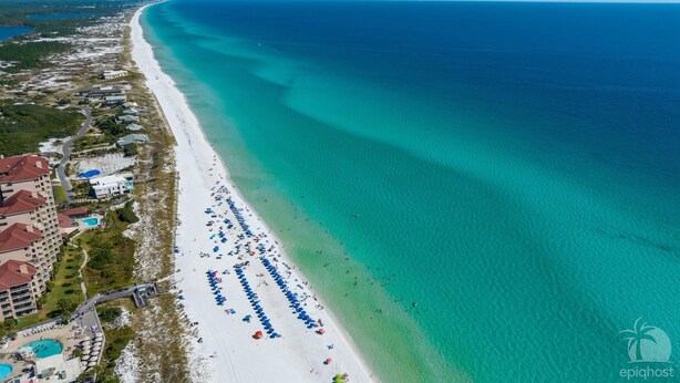 An aerial view of a beach with a long stretch of white sand, a clear blue ocean, and a resort area with buildings and a pool. - KonaKai-Sandestin® 2BR/2.5BA Views-Walk to Beach! (Miramar Beach)