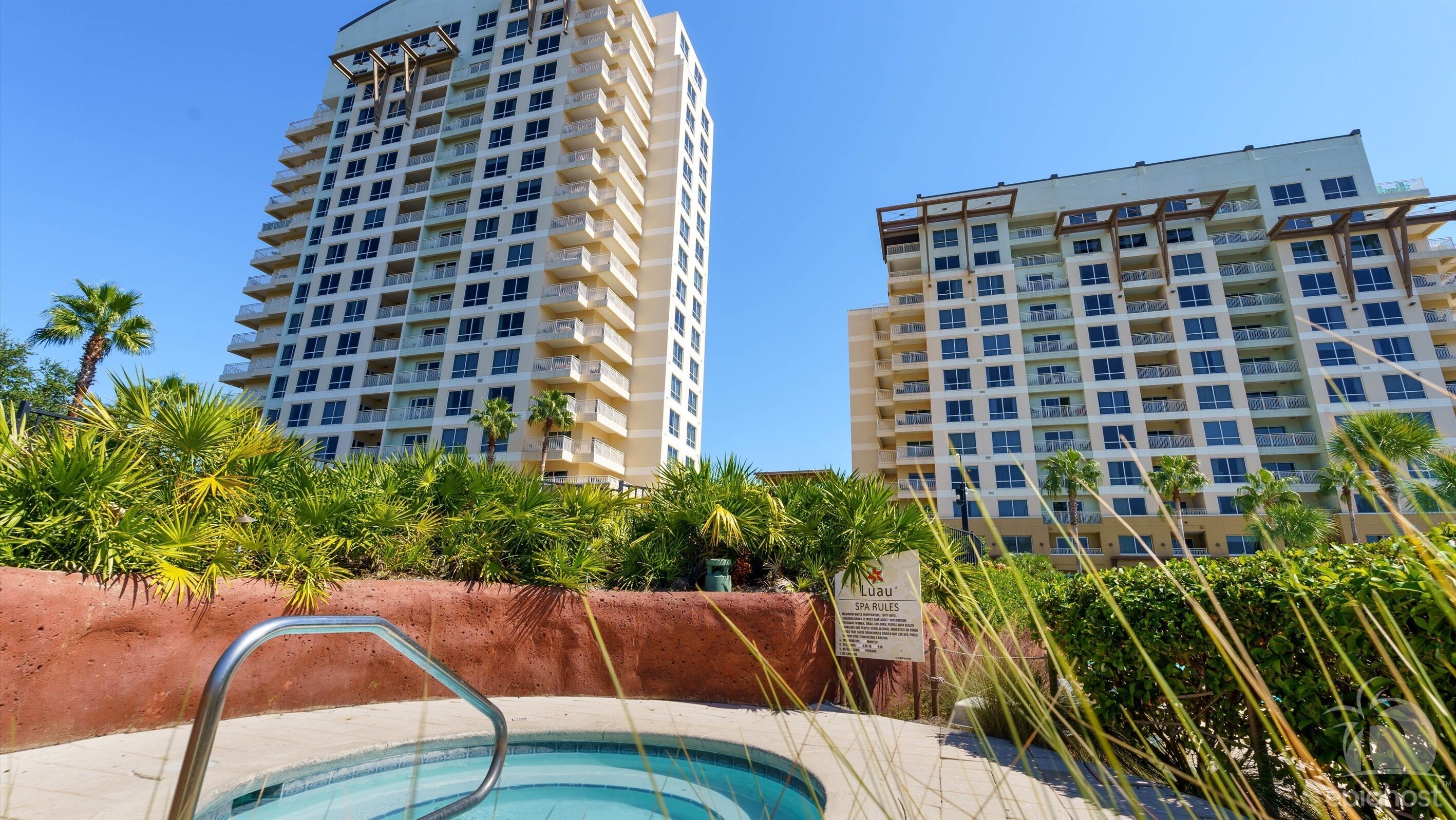 A hotel with multiple high-rise buildings, a swimming pool, and lush greenery.
