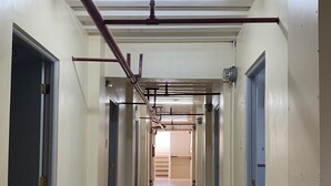 A long, narrow hallway with doors on both sides, leading to a staircase at the end. - Lawton Residences powered by Cocotel (Taguig)
