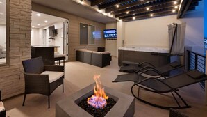A modern outdoor living area with a fire feature, seating, and a TV screen. - Bare Feet Retreat by RedAwning (St. George)