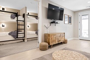 A modern room with bunk beds, a TV, a wooden cabinet, and a large window. - Bare Feet Retreat by RedAwning (St. George)