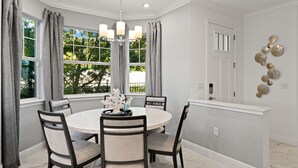 A dining area with a round table, four chairs, a chandelier, and a window with curtains. - Paradise in naples, few mins from downtown, beaches, mercato ...... (Naples)