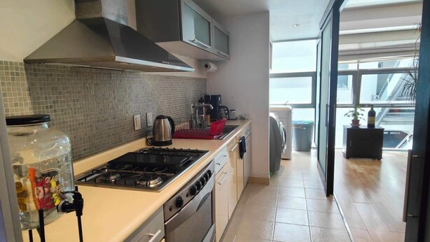 Een moderne keuken met een gasfornuis, oven en magnetron, een groot raam en uitzicht op buiten.