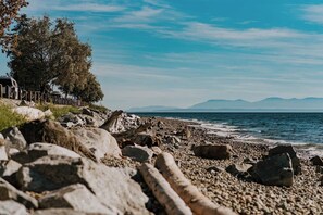 A rocky shoreline with a clear view of the sea and distant mountains.