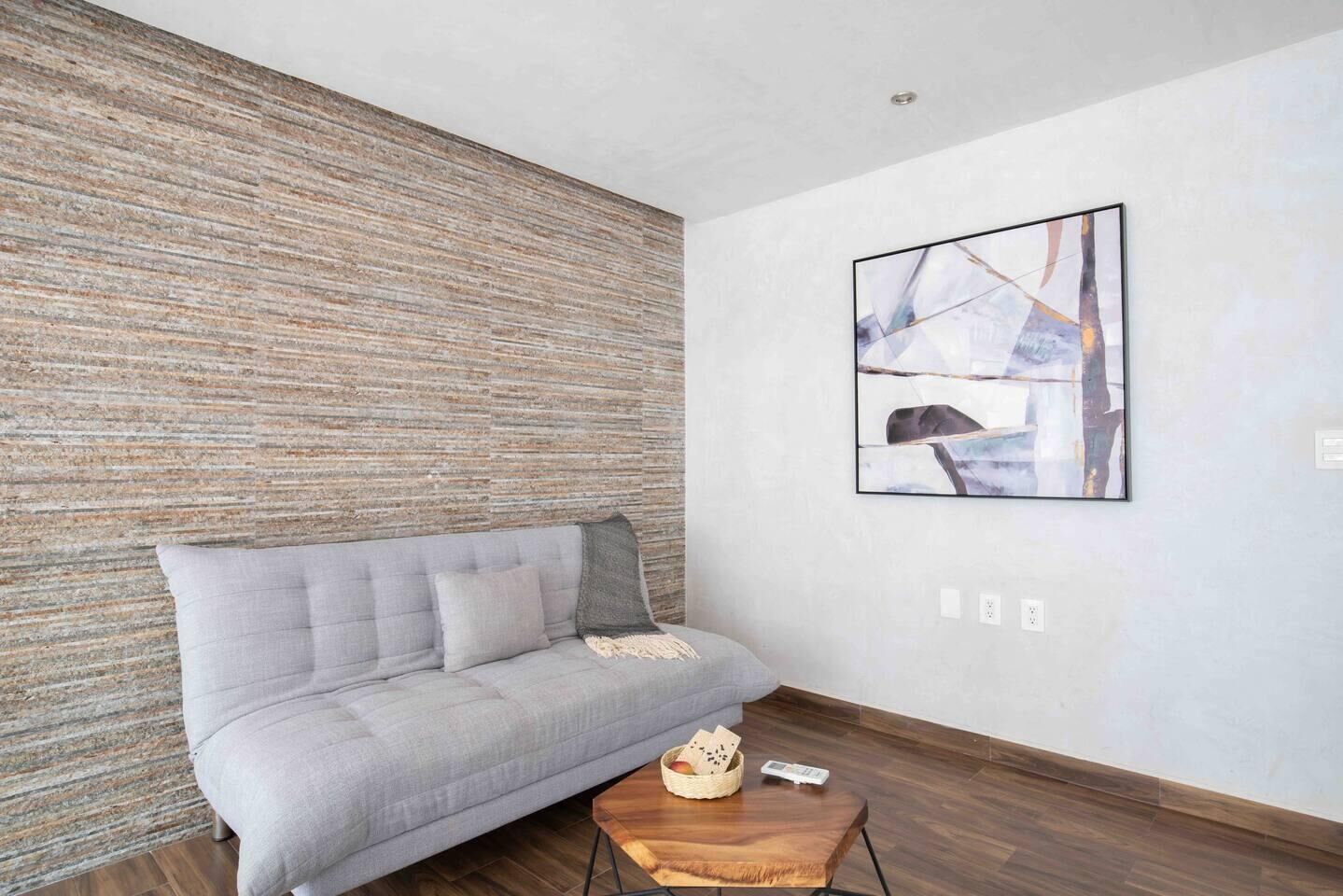 A modern living room with a grey sofa, a wooden coffee table, and a textured wall.