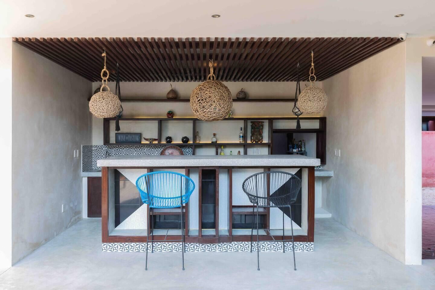 Una cucina moderna con isola centrale, due sedie blu e una lampada a sospensione.
