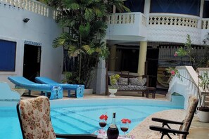 Piscina interior con sillas de descanso, un sofá y una mesa con bebidas.