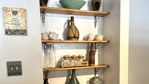 Une étagère murale agrémentée de divers objets décoratifs, notamment des vases, des pots et une petite plante.