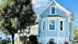 A two-story house with a prominent bay window and a large tree in front. - Modern Victorian - 1910 Guesthaus (Hermann)