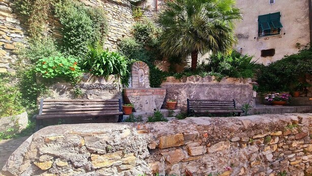 Un mur de pierre avec un banc et des plantes en pot.