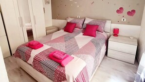 Une chambre à coucher comprenant un lit, deux tables de chevet, une armoire et un mur décoré de motifs en forme de cœur.