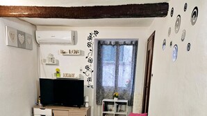 Un salon équipé d’un téléviseur à écran plat, d’un canapé, d’une table à manger et d’une petite plante.