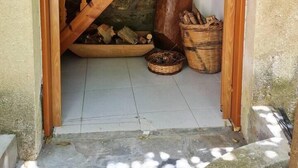 A wooden staircase leading to a stone wall, with firewood and baskets on the floor.