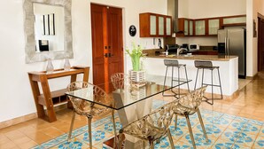 Una cocina moderna con una mesa de comedor de vidrio, sillas de madera y una isla central.